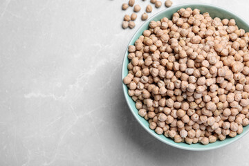 Chickpeas in bowl on light grey table, top view. Space for text