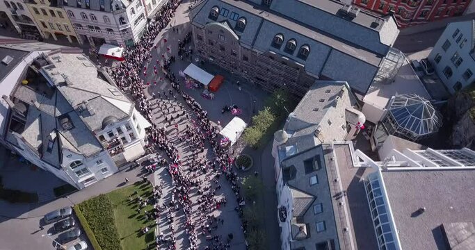 Truly amazing, cinematic aerial drone time lapse of marching people amongst the famous art nouveau buildings of Alesund, Norway's most beautiful town, during national or constitution day, 17th of May.