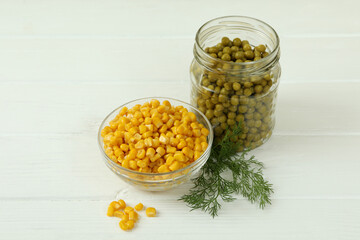 Canned peas and corn on white wooden background