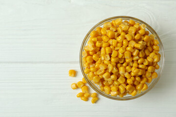 Bowl with canned corn on white wooden background