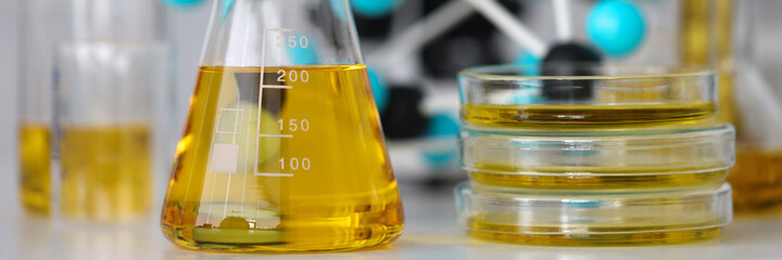 Glass test tubes with yellow viscous liquid stand on table in chemical laboratory closeup. Checking...