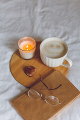 Breakfast in bed. Coffee mug, heart-shaped cookies, book, glasses, candle, wooden tray. Women's Day. Cozy.