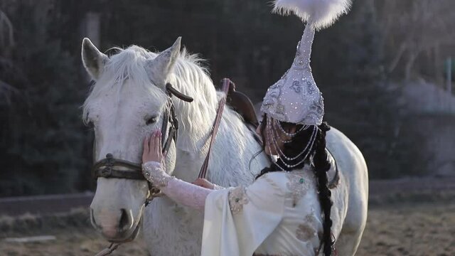 An Asian girl in a national costume is riding a horse. Kyrgyz national costume.