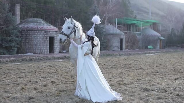 An Asian girl in a national costume is riding a horse. Kyrgyz national costume.
