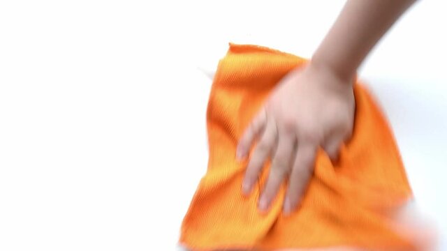 girl wipes a saw from a white table with an orange rag on a white background.