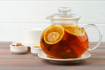 Glass teapot with black tea and pieces of citrus