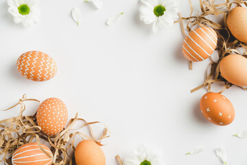 Happy Easter concept. Frame of elegant Easter eggs and spring flowers on white background. Flat lay, top view, copy space.