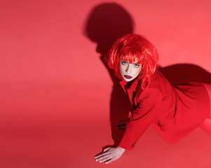 Fashion concept. Lady crawls on floor. Young woman in red. Girl on mysterious face in red formal jacket, red background.