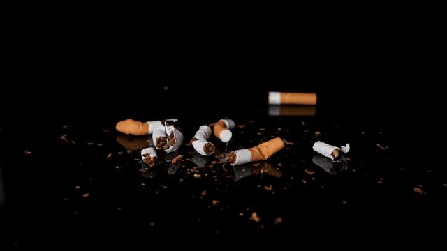 Used and stubbed out cigarettes falling on tobacco in slow motion.
