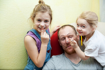 Little children drawing on face of their sleeping dad