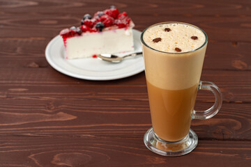 Cup of latte coffee with piece of berry cheesecake