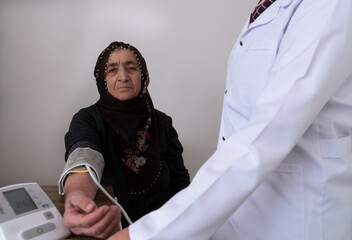 An elderly Muslim hijab woman who had her blood pressure measured. Old people, public health. Patient and doctor, nurse at the hospital. Health checks. hypertension