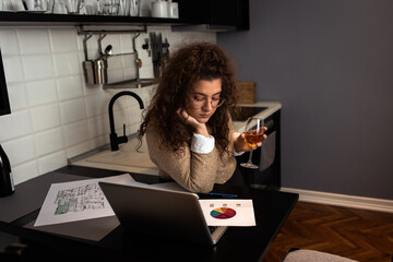 Portrait of young woman working at home in kitchen using laptop.	