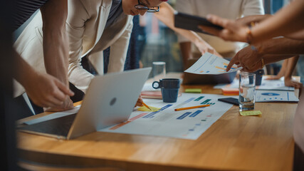 Diverse Multi Ethnic Team of Professional Businesspeople Meeting in the Modern Office Conference Room. Creative Team Gathers Around Table to Discuss App Design, Use Laptop. Focus on Desk and Hands