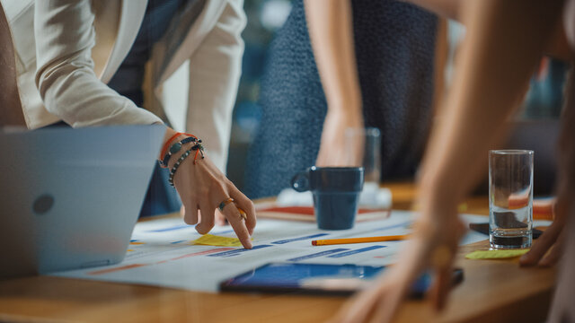 Diverse Multi Ethnic Team of Professional Businesspeople Meeting in the Modern Office Conference Room. Creative Team Gathers Around Table to Discuss App Design, Analyze Data. Focus on Desk and Hands