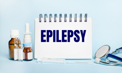 On a light background, a syringe, a stethoscope, vials of medicine, an ampoule and a white notepad...