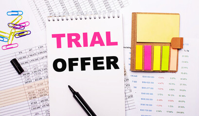 A notebook with the words TRIAL OFFER, a marker, colored paper clips and bright note paper lie on...