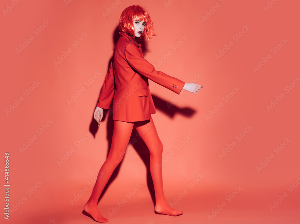 Wall mural woman in red. fashion concept. girl on mysterious face in red formal jacket, red background.