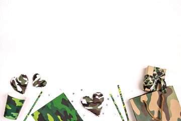  Party set with camouflage glasses, straws, napkins and gifts on white background with copy space for text.
