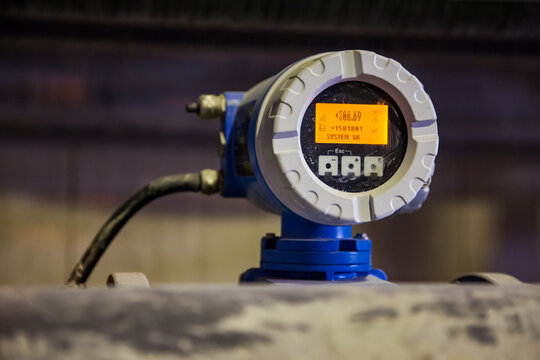 Close Up Photo Of Dirty Electronic  Flow Meter With Digital Display In Factory Workshop. Blurred Background, Low Depth Of Field.