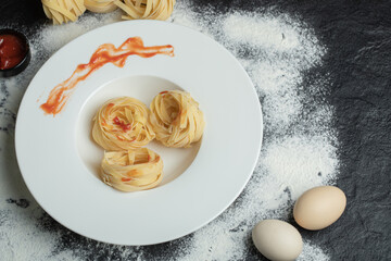 A white plate of uncooked nest noodles with eggs