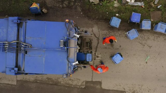 Aerial top down ascending shot of Garbage truck collecting trash bins
