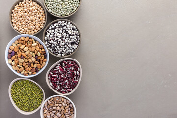 Different types of legumes in bowls, green and yellow peas, chickpeas and peanuts, colored beans and lentils, mung beans and beans, top view