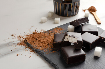 Tasty candies with chocolate glaze, sugar, cocoa on the white table