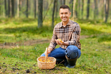 picking season and leisure people concept - happy smiling middle aged man with wicker basket and mushrooms in autumn forest