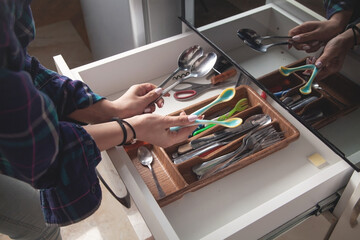 Woman hand holding spoons in kitchen.