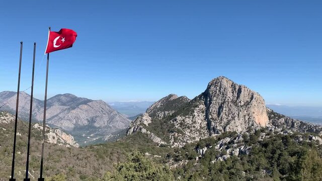 Flag of Turkey waving in the wind against deep blue sky and mountains. The national flag of Turkish flutters in the wind with nature landscape background. 4k 60 fps 