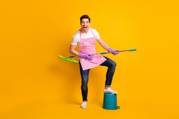 Full size portrait of positive man put leg on bucket hands playing guitar mop isolated on yellow color background