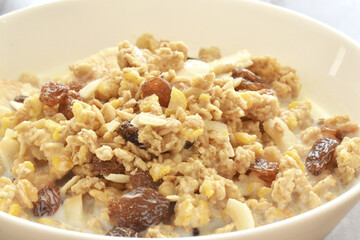 Muesli fruit and fiber cereal with dry oat, corn, banana, raisin, and apple with milk.