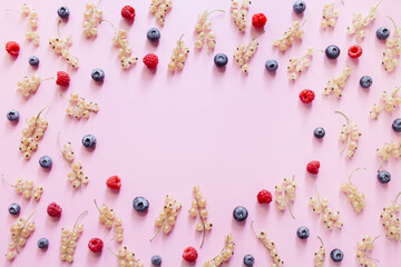 Colorful pattern of blueberries, currant berries white, raspberries on pastel pink background. Flat lay, top view, copy space.