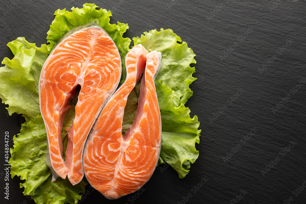 Wall mural fresh salmon steak on lettuce leaf, stone background, flat lay, place for text