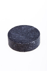 Black round piece of soap on a white background. 