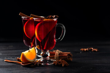 mulled wine with spices poured into glass glasses on a wooden dark background