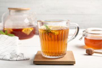 Hot tea with mint and lemon slices on white table, closeup