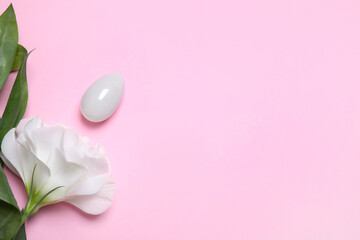 Beautiful flower and jade egg on pink background, flat lay with space for text