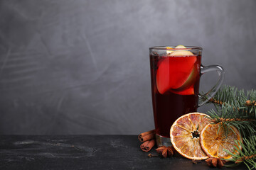 Tasty aromatic mulled wine on black table, space for text
