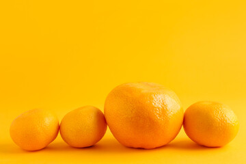 Ripe delicious tangerines and one bigger than others on orange background. Space for text
