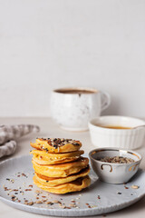  Stack of golden pancakes with various seeds and coffee. 