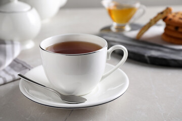 Cup of hot tea and spoon on light grey table
