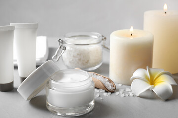 Fototapeta na wymiar Composition with cosmetic products and candles on grey table