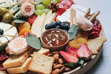 Wooden plate full of assorted appetizers on table, closeup