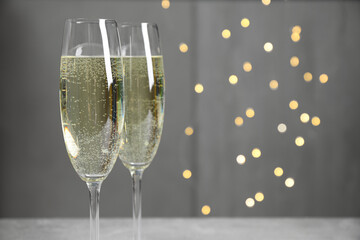 Glasses of champagne on light grey background with blurred lights. Space for text © New Africa
