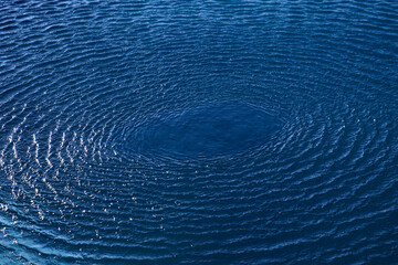 Splash: concentric circle waves on blue fresh sea water; color photo.