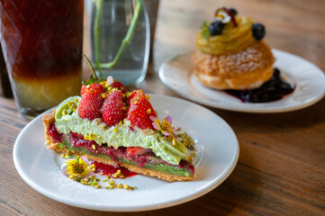 Pistachio strawberry tart filled with strawberry jam on wooden background.