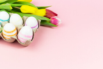 Easter painted eggs with tulips on a pink background. Copy space. Easter celebration concept.