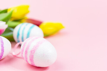 Easter painted eggs with tulips on a pink background. Copy space. Easter celebration concept.